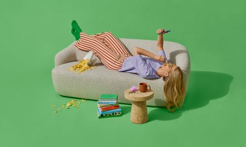 dame ligger på sofa med mobil og venter på pakkelevering