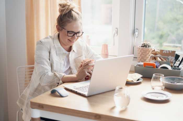 En kvinne som jobber på en laptop på kjøkkenet