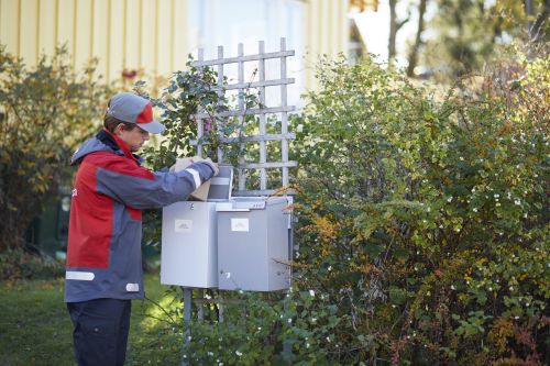 En Postbud leverer en pakke i en postkasse