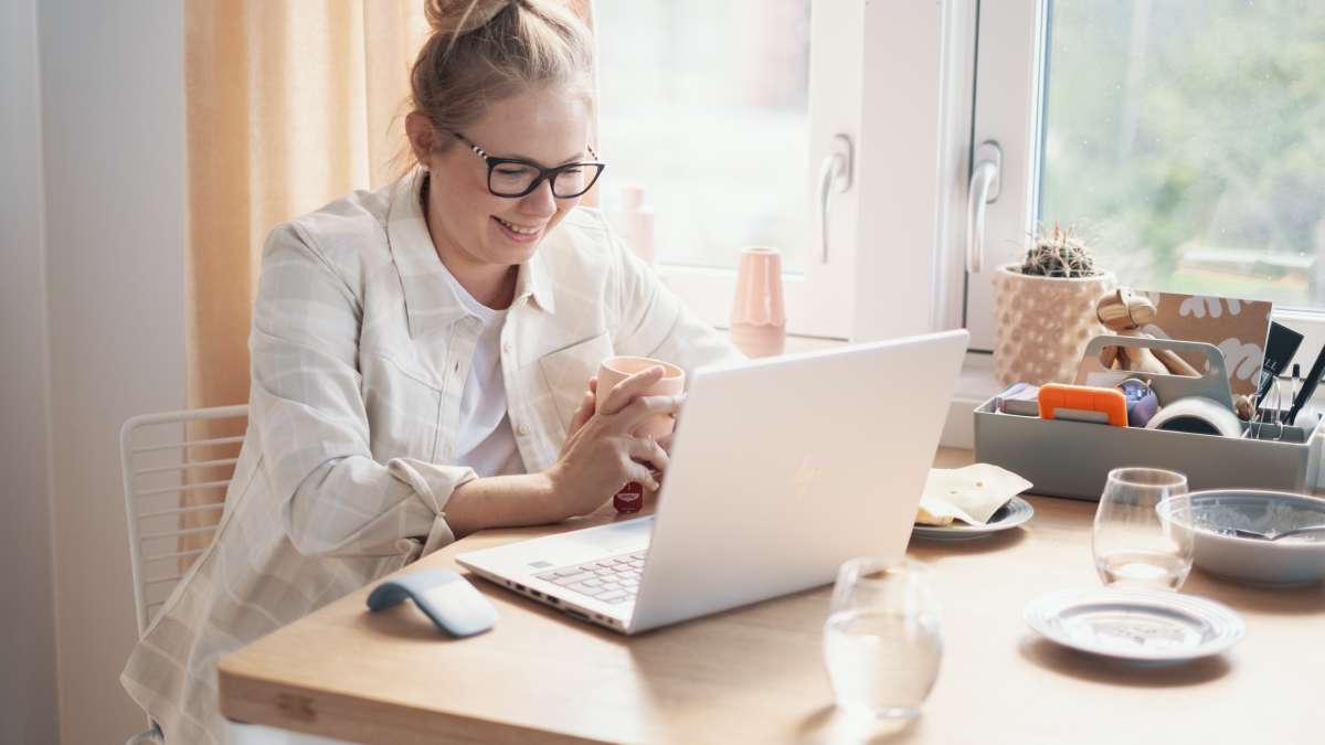 En kvinne som jobber på en laptop på kjøkkenet