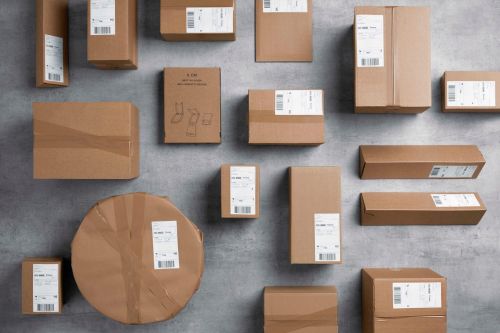 Pakker i gråpapir i ulike format ligger spredd utover et grått gulv.