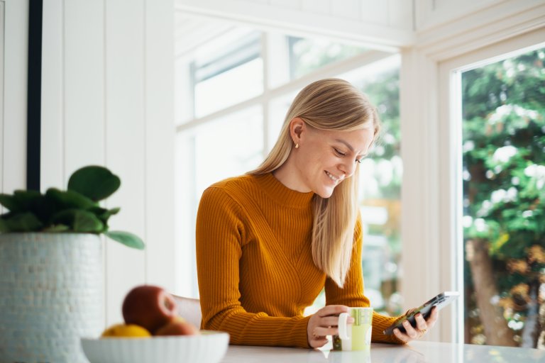 Kvinne ser på telefonen og smiler