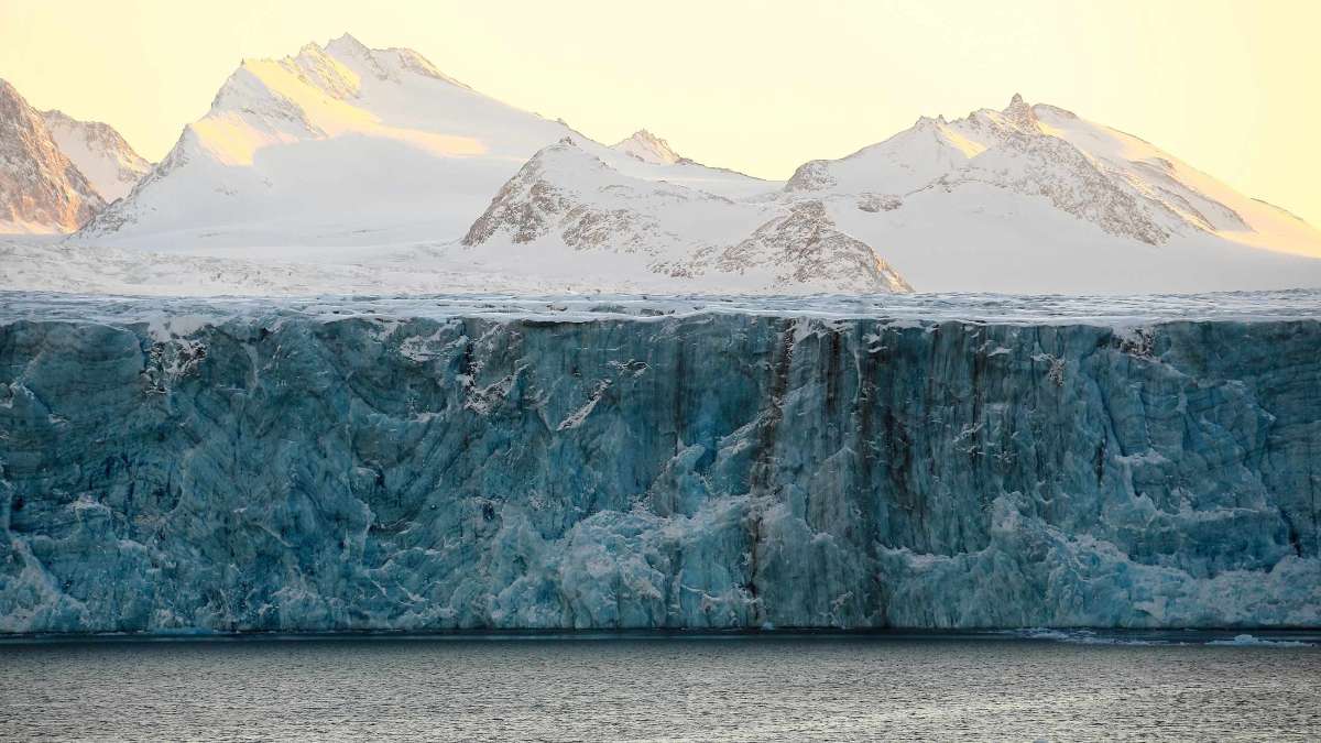 Svalbard-landskap med snøkledde fjell, isbre og hav.