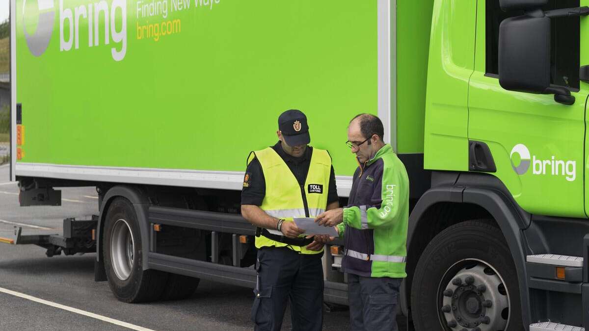 Bring sjåfør og tollkontrollør snakker sammen foran en Bring lastebil.